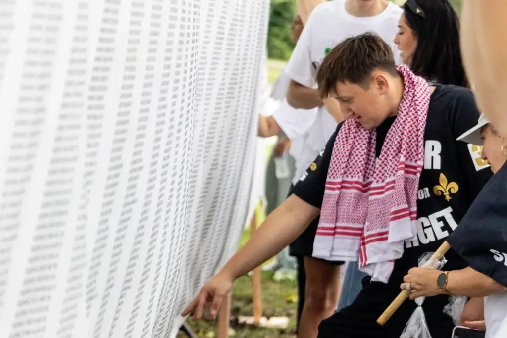 Samil Krajina searches through a banner of names of people who died during the Srebrenica genocide for his grandfather Mustafa Music and his uncle Muhidin Music during a commemoration of the tragedy in downtown St. Louis on Saturday, July 12, 2025. The banner was set up by the Srebrenica Remembrance Coalition to honor those lost during the genocide in July 1995.
Zachary Clingenpeel